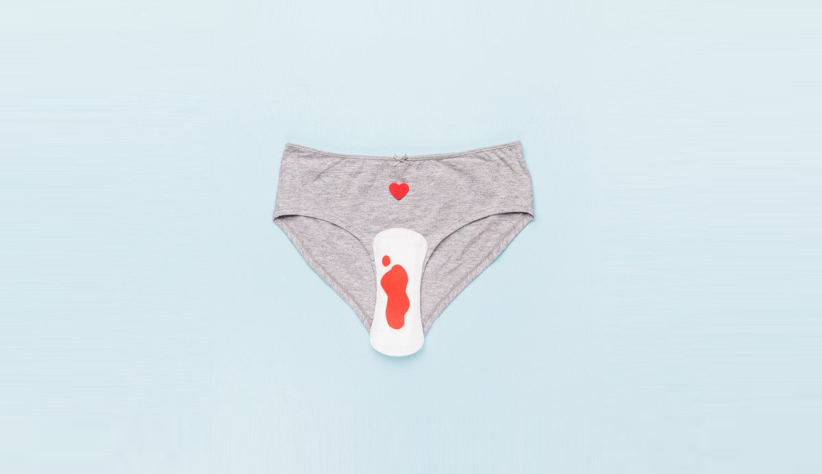 Heavy flow sanitary pads: Gray women's underwear with a small red heart design, featuring a white feminine hygiene product placed prominently on top.