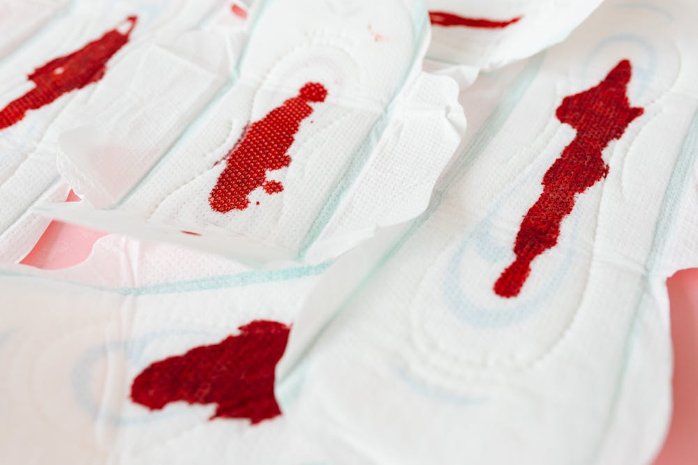 Pads for different flow levels: A collection of feminine hygiene pads with red stains, arranged on a soft surface.