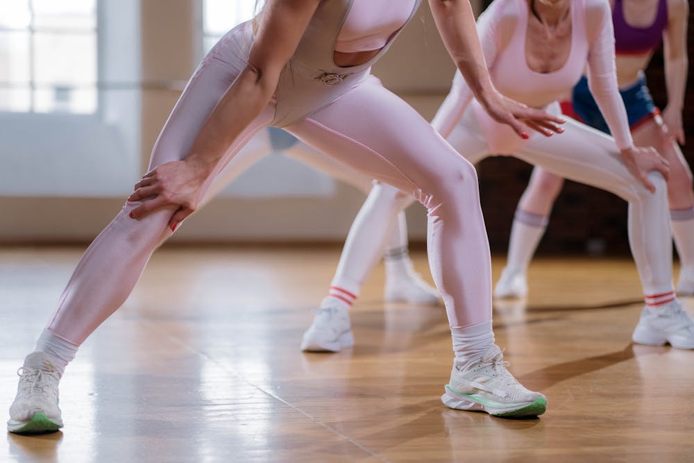 Best pads for light flow: A group of women in fitness attire stretching in a dance studio, emphasizing movement and teamwork in a bright space.